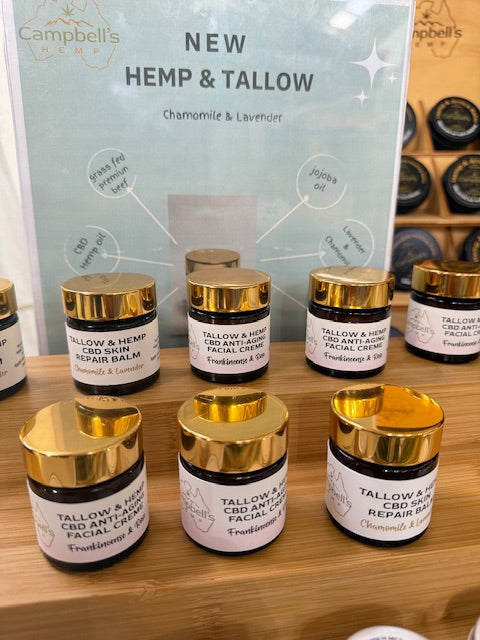 Collection of tallow and hemp skincare products with gold lids on a wooden surface, branded as Campbell's.