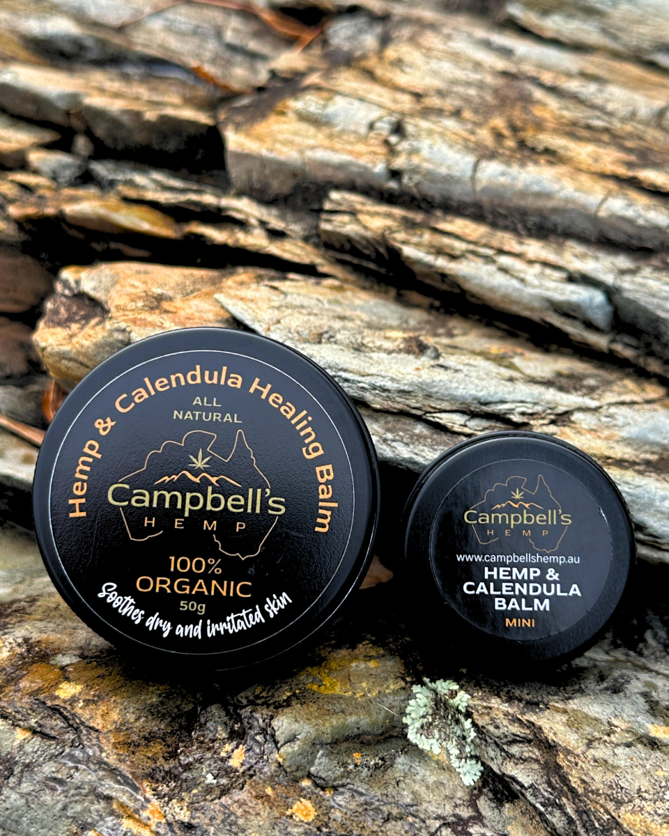 Hemp and Calendula Healing Balm in a small round tin, displayed with fresh calendula flowers and natural ingredients, evoking a soothing, organic skincare aesthetic.
