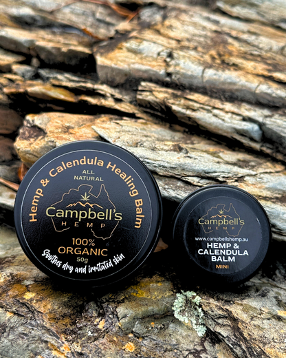 Hemp and Calendula Healing Balm in a small round tin, displayed with fresh calendula flowers and natural ingredients, evoking a soothing, organic skincare aesthetic.
