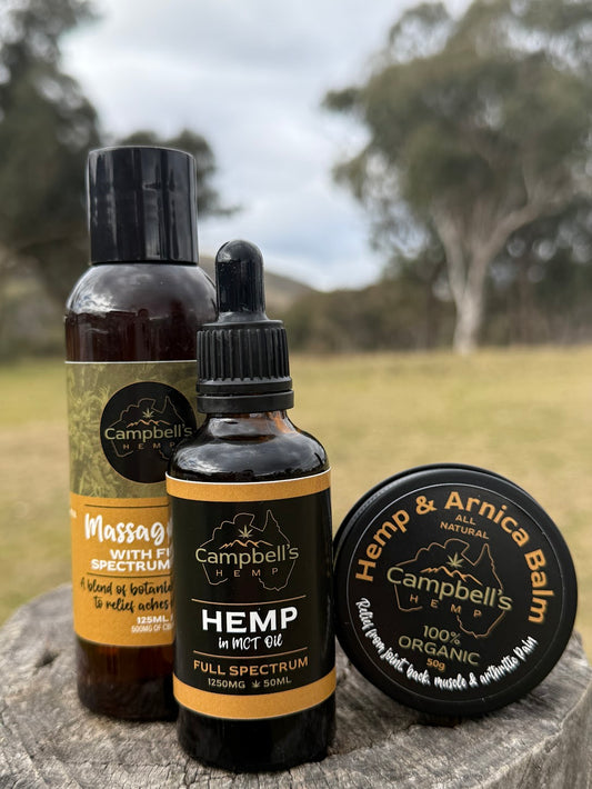 Campbell's Hemp products including a bottle, dropper, and balm on a stone surface with a natural background. The Hemp Trio Pain Relief Bundle – includes massage oil, hemp balm, and hemp oil for natural muscle relief, pain support, and skin hydration


